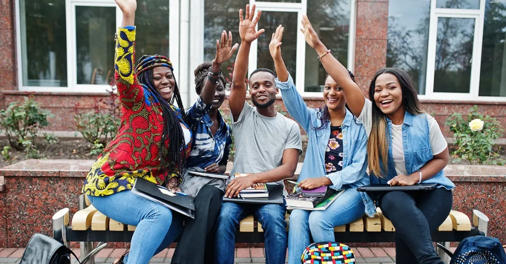 Four young people on a bench raise their hands enrolled for bursaries for 2025